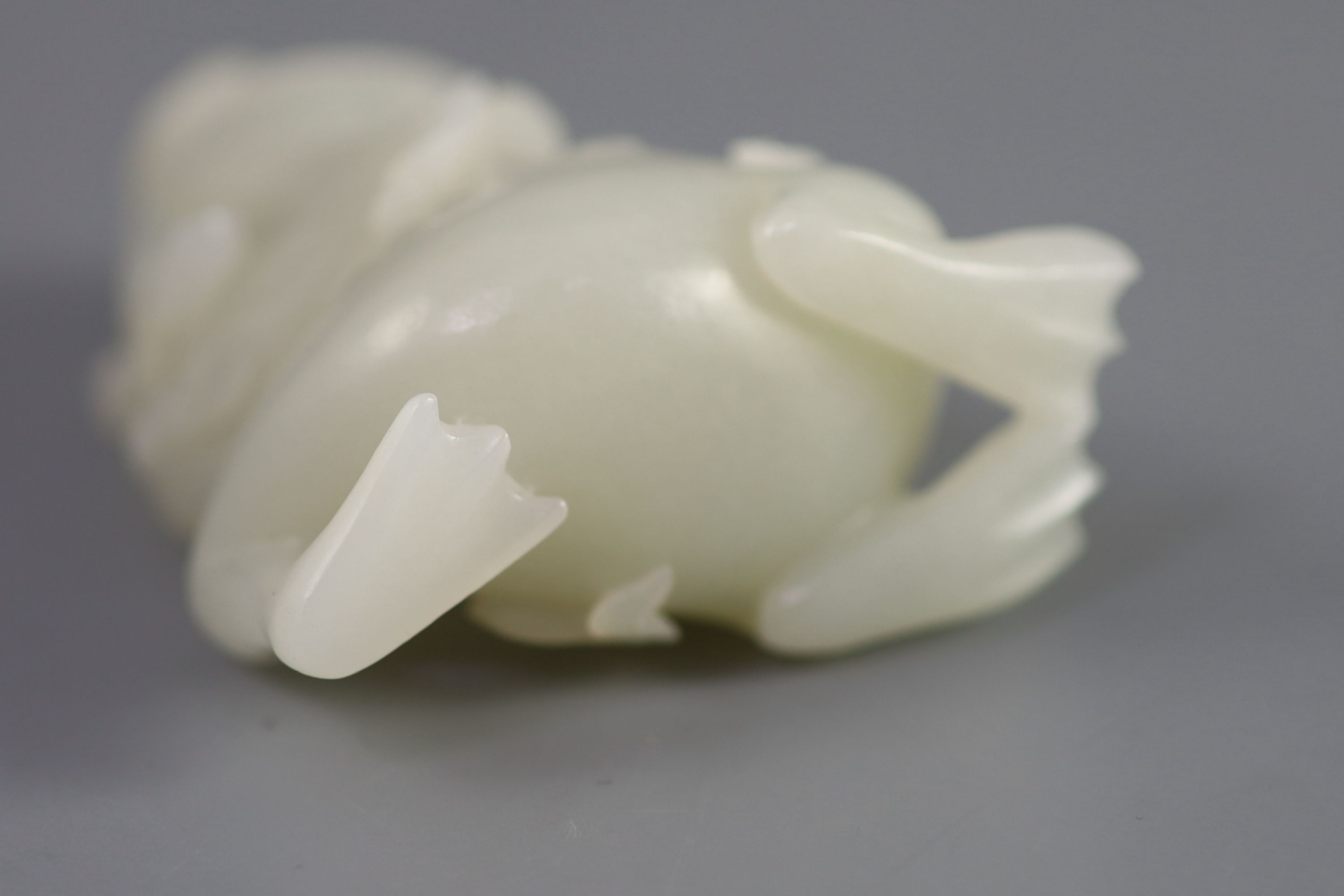 A good Chinese pale celadon jade group of Liu Hai and the three legged toad, 18th century, 8cm high, the wood stand carved with swirling waves